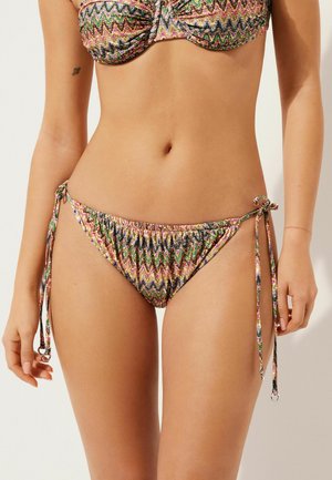 Bikini mit buntem Zickzackmuster und geraffter Textur. Die Hose verfügt über verstellbare Seitenschnüre und einen niedrig geschnittenen Bund.