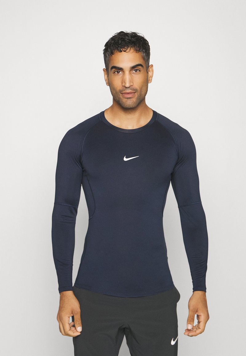 Langärmliges, navyfarbenes Sportshirt mit figurbetontem Design. Verfügt über ein weißes Nike-Logo auf der Brust und einen glatten, elastischen Stoff.