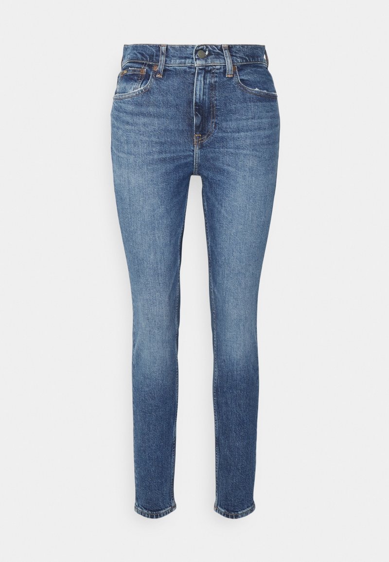 Jeans slim fit de tiro medio en denim azul oscuro con una textura desgastada, que cuentan con cinco bolsillos y un cierre de botón. Estilo clásico con costuras visibles.