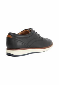 Black leather casual shoe with brown trim, white sole, and black laces, shown from back-side angle on white background.