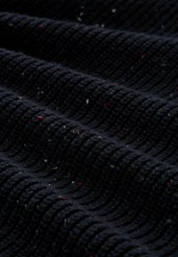 Marineblauwe textuurstof met een ribbelpatroon, met kleine spikkels in rood en wit, die zachte, geweven vezels tonen.
