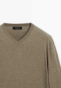 Maglione khaki a V in misto di tessuti morbidi, con bordi a coste e una superficie liscia per comfort e uso quotidiano.
