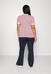 Różowa koszulka z krótkim rękawem z białymi akcentami, w połączeniu z granatowymi spodniami w dzwon. Gładki materiał o luźnym kroju i klasycznym fasonie kołnierzyka.