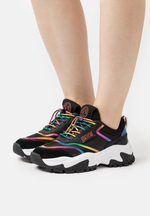 Baskets noires avec accents multicolores, matériaux en mesh et daim, semelle intermédiaire blanche épaisse et lacets arc-en-ciel. Logo présent sur la languette.
