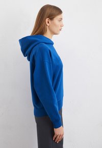 Felpa blu con cappuccio e vestibilità comoda, dotata di polsini e orlo a costine, con un logo ricamato sul davanti. Tessuto morbido.