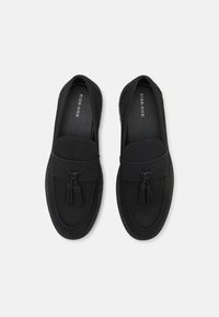 Sorte loafers laget av glatt materiale med dekorative dusker og rund tå. Har minimal søm og er slip-on design.