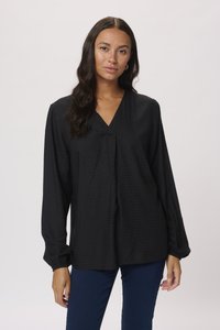 Black, long-sleeved blouse with a V-neckline, textured dots, and gathered cuffs. Relaxed fit, paired with dark blue jeans.