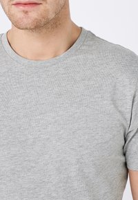 Graues kurzärmliges T-Shirt mit Rundhalsausschnitt, aus weichem Strukturstoff gefertigt, mit glatter Oberfläche und dezentem Melange-Muster.