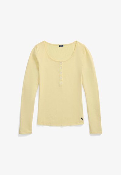 Chemise henley à manches longues jaune clair avec encolure dégagée, six boutons sur le devant et petit logo noir brodé près de l'ourlet inférieur.