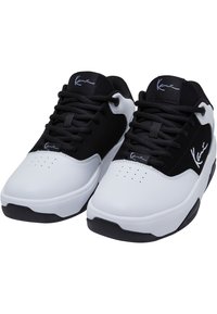 Černobílé sportovní boty s hladkým koženým svrškem, polstrovaným límcem, šněrovacím designem, perforovanou špičkou a černou gumovou podrážkou.