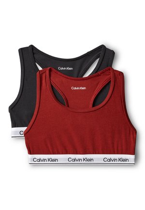 Due reggiseni sportivi Calvin Klein, uno nero e uno rosso, con design racerback e fasce elastiche bianche marchiate con la scritta Calvin Klein.