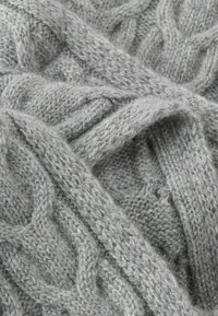 Jasnoszare dzianinowe tkanina z wełny z wzorem warkocza o grubych i cienkich pasmach, ukazująca teksturę i miękkość.