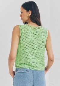 Lichtgroene gehaakte tanktop met een losse pasvorm, voorzien van een textuurpatroon en een rechte zoom. Gecombineerd met denim jeans.
