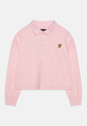 Jasnoróżowa, krótką polo wykonaną z miękkiego materiału, z kołnierzykiem, trzema guzikami i małym logo żółtego motyla na piersi.