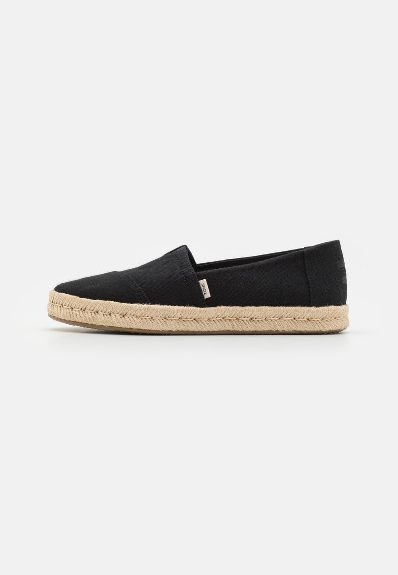 Juodas kanvas espadrilė su jūrinio virvės padu. Turi slip-on dizainą ir mažą prekės ženklo etiketę šone. Lygi tekstūra.