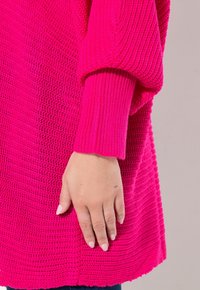 Helles rosa gestricktes Sweatshirt mit lockerem Schnitt, mit gerippten Bündchen und strukturiertem Muster, das bis zur Mitte des Oberschenkels reicht.