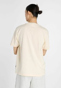 Lys beige bomulds t-shirt med korte ærmer, afslappet pasform og rund halsudskæring. Har et lille label på sidesømmen.