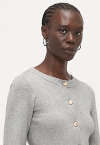 Gray knitted cardigan with a round neckline, featuring four textured gold-tone buttons and ribbed detailing on the collar and cuffs.