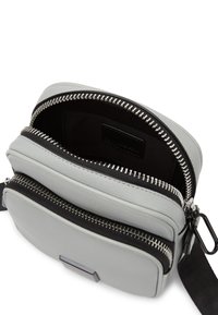 Borsa a tracolla in pelle grigia con doppie tasche con zip, fodera in tessuto nera, hardware in argento e una tracolla rimovibile per maggiore versatilità.