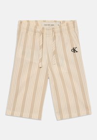 Béžové a krémové vertikálne pruhované šortky s elastickým pásom, šnúrkou a čiernym vyšitým logom "CK" na pravej stehnej časti.