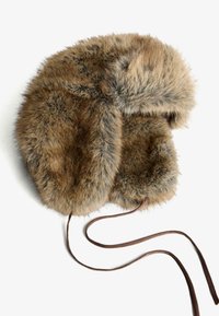 Barna prémes sapka fülvédővel, puha textúrával, megkötőkkel a biztos illeszkedésért és enyhén lekerekített tetejével. Díszítésként sötétebb prém foltok találhatók rajta.