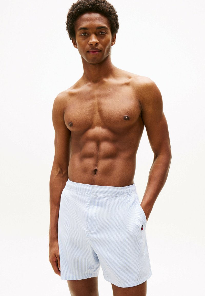 Shorts de bain rayés bleu clair avec une taille élastique et des poches. Le tissu semble lisse avec un léger éclat.