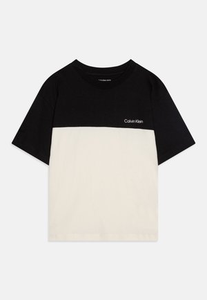 Camiseta color bloque en negro y crema, hecha de algodón, con cuello redondo, mangas cortas y un pequeño logo de Calvin Klein en el pecho.