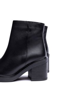 Schwarze Leder-Stiefeletten mit klobigem Blockabsatz und glatter Textur. Verfügen über ein schlichtes Design mit minimalen Nähdetails.