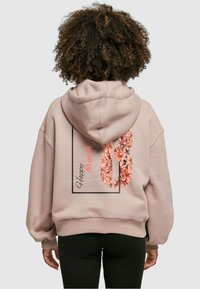Pink hoodie featuring a floral design with "Happy March 8" text. It has a spacious cut, long sleeves, and a soft texture.