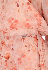 Blumenkleid aus weichem pinkfarbenem Stoff mit orangefarbenen und roten abstrakten Mustern, das zarte vertikale Streifen aufweist und ein eingenähtes Etikett besitzt.
