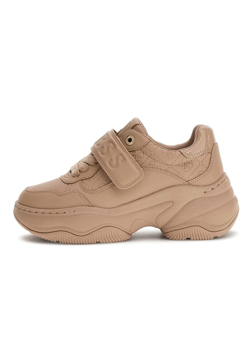 Masywne beżowe sneakersy z wytłoczonym paskiem z logo, teksturowaną skórzaną cholewką i grubą, rzeźbioną gumową podeszwą, pokazane w profilu bocznym.