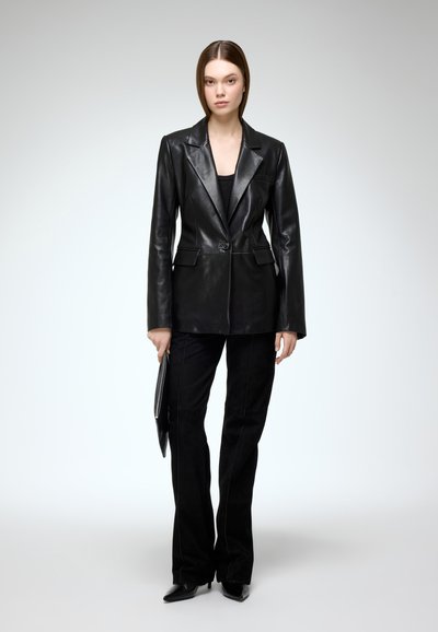 Black leather blazer with a notched lapel and single button closure. Paired with black suede pants and pointed toe heels. Sleek and fitted design.