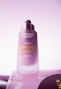 Fioletowa szklana butelka serum z okrągłym aplikatorem. Posiada biały i złoty nadruk. Gładka powierzchnia, cylindryczny kształt i matowe wykończenie.