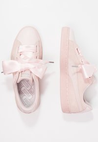 Tenisky Puma v jemné růžové barvě s kombinací texturované kůže a nubuku. Mají nadměrné saténové šňůrky a vzor na stélce s logem.