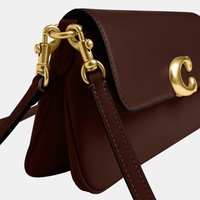 Bolso bandolera de piel marrón oscuro con herrajes en tono dorado y cierre en forma de la letra C, con correas de hombro ajustables.