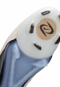 Suola della scarpa con una sezione traslucida blu, parte superiore beige, accenti neri e un logo circolare dorato con un design stilizzato della "S".
