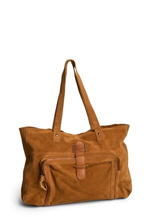 Sac cabas en daim marron avec doubles bretelles, poche zippée à l'avant et sangle décorative en cuir avec clous métalliques.