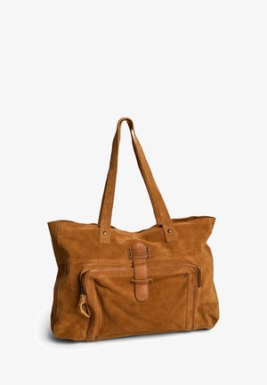 Sac cabas en daim marron avec doubles bretelles, poche zippée à l'avant et sangle décorative en cuir avec clous métalliques.