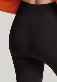 Czarne legginsy z wysokim stanem wykonane z gładkiego, elastycznego materiału, z bezszwowym designem i elastycznym pasem dla komfortowego dopasowania.