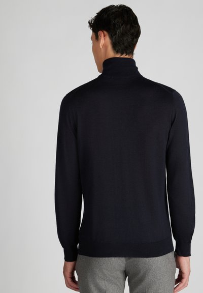 Granatowy sweter z golfem, z długimi rękawami i dopasowanym krojem, wykonany z miękkiego, lekkiego materiału. Bezszwowe plecy z prążkowanymi mankietami.