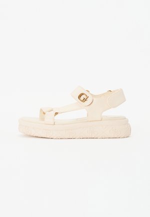 Sandali platform beige con due cinghie regolabili e dettagli in oro. La suola presenta un motivo floreale testurizzato.