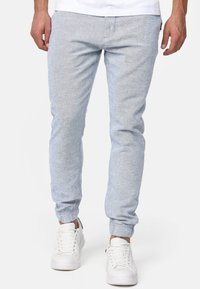 Pantalones de ch�ándal azul claro hechos de una tela texturizada, con una cinturilla y puños elásticos, combinados con zapatillas blancas.