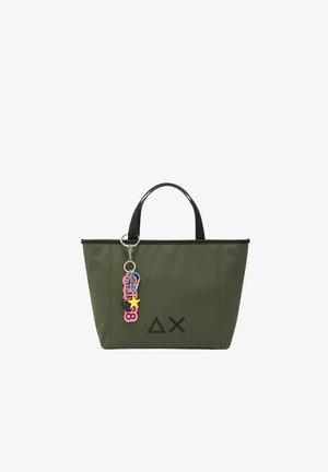 Olive green tote bag with black trim, featuring two handles and a charm with colorful accents. Simple geometric logo printed on one side.