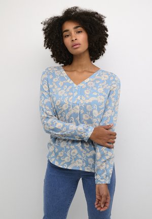 Himmelblaues Langarmbluse mit V-Ausschnitt, versehen mit beigen Blumenmustern. Der Stoff hat eine glatte Textur, mit gerafften Manschetten und einer lockeren Passform.