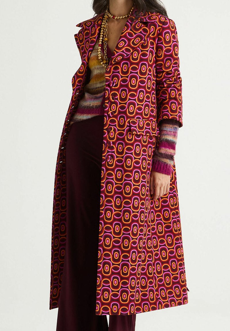 Cappotto lungo con motivo geometrico vivace in rosa, arancione e viola. Ha un design su misura con colletto e tasche laterali.