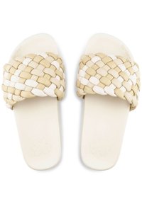 Woven slide sandals featuring a braided strap in beige and white, with a smooth white footbed and a flower emblem on the sole.