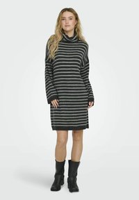 Vestido de suéter gris a rayas con cuello alto, mangas largas y un corte holgado, combinado con botas negras hasta la rodilla. Material suave de mezcla de lana.