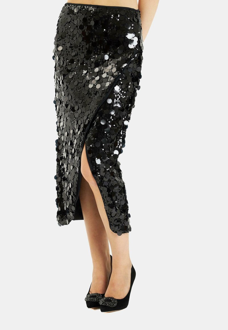 Falda lápiz de lentejuelas negras con una abertura alta hasta el muslo, que presenta lentejuelas redondas, una textura suave y un diseño ajustado. Combinada con zapatos negros.