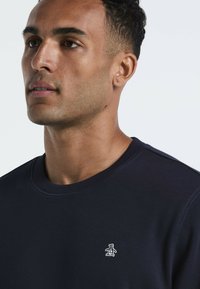 Marine crewneck sweatshirt gemaakt van zachte stof, met een klein wit pinguïnlogo op de linkerkant van de borst en ribgebreide hals en manchetten.