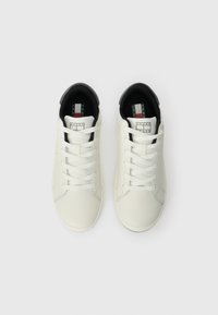 Witte leren sneakers met zwarte accenten, voorzien van platte veters, een ronde neus en een logotag op de tong met rode en blauwe strepen.